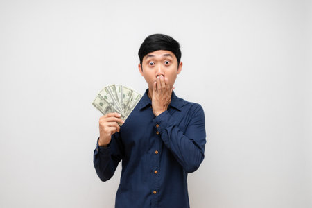 Asian young man feels excited about earn a lot of money in his hand isolatedの写真素材