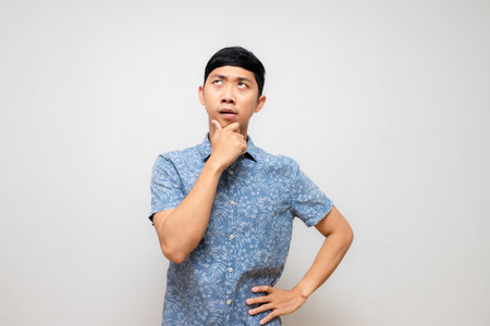 Young asian man blue shirt posing thinking and feels hesitate isolatedの写真素材