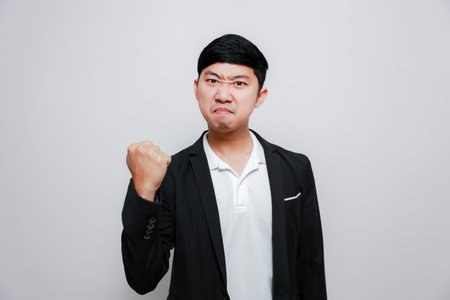 Asian man black suit confident look success show fist up isolatedの写真素材