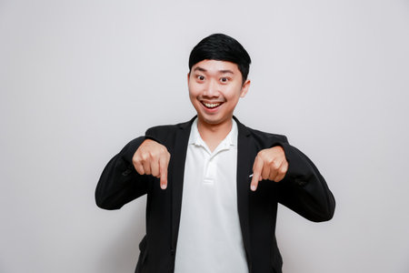 Cheerful business man gesture point finger down isolatedの写真素材