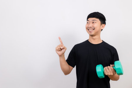 Positive asian man happy smile black shirt work out with dumbbell gesture point finger isolatedの写真素材
