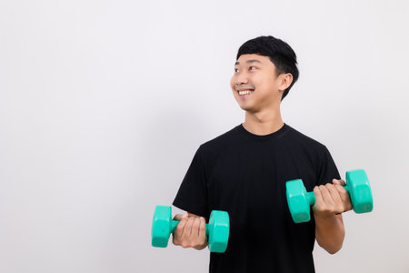 Positive asian man happy smile black shirt work out with dumbbell smile and look at space isolatedの写真素材