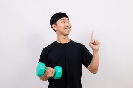 Positive asian man happy smile black shirt work out with dumbbell gesture point finger isolatedの写真素材