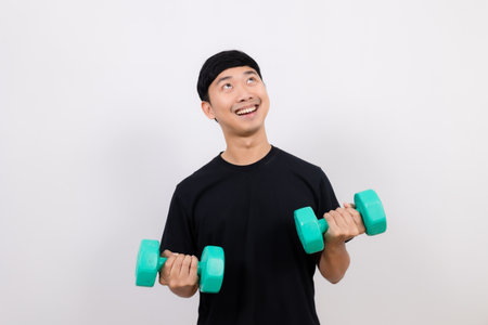 Positive asian man happy smile black shirt work out with dumbbell smile and look up at space isolatedの写真素材