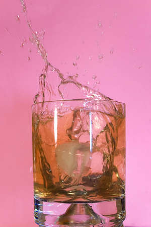 Ice floe falling into whisky glass causing from the splashesの写真素材