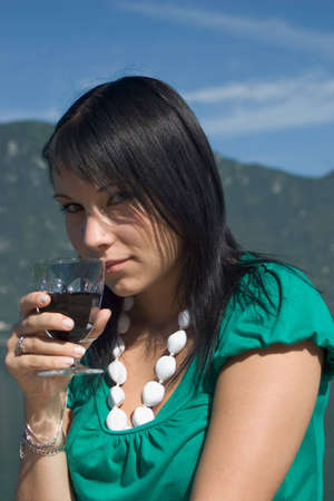 Woman tasting of the wine at the edge of a lake