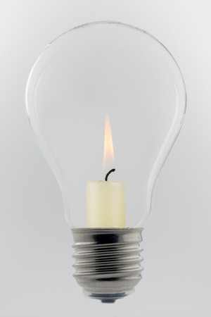 Conceptual glass light bulb with burning candle insideの写真素材