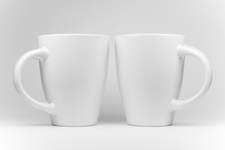 Two white mugs in a mirrored arrangement in high-keyの写真素材