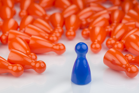 Conceptual orange game pawns and a blue play pawn as abstract display of inequality in color and number ofの写真素材