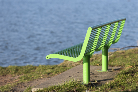 Green bench as street furniture in a grassy area on the waterfrontの写真素材