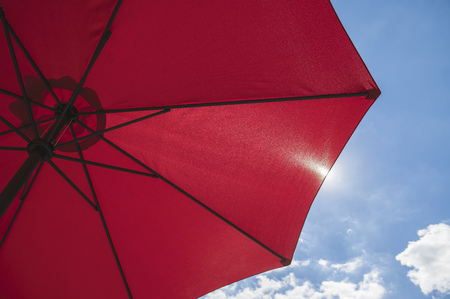 Red beach parasol against a blue sunny summer skyの写真素材