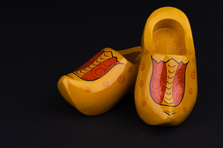 Yellow colored and painted characteristic Dutch wooden shoes against a black backgroundの写真素材