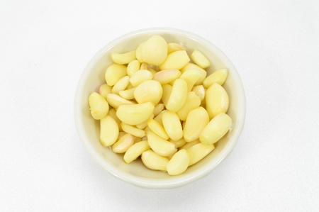 Fresh peeled garlic in a bowl, isolated on white background の写真素材