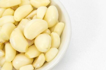Fresh peeled garlic in a bowl, isolated on white background の写真素材
