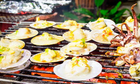 Grilled scallops topped with butter, garlic and parsley on flaming grill の写真素材