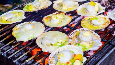 Grilled scallops topped with butter, garlic and parsley on flaming grill の写真素材