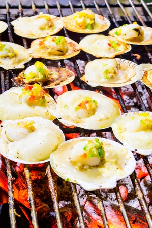 Grilled scallops topped with butter, garlic and parsley on flaming grill の写真素材
