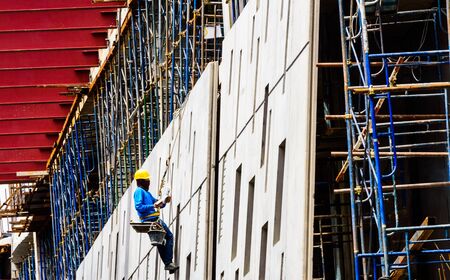 A Construction Workers high up on the wall of a new building のeditorial素材