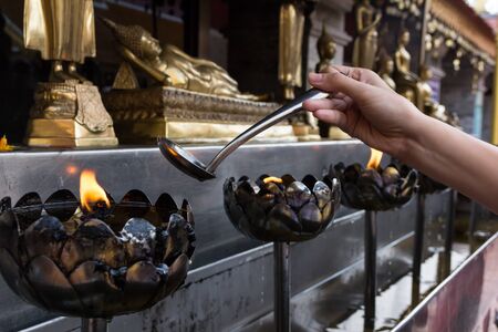 Oil filling in Thai style metal candle in Thai temple, Chiang Mai, Thailandの写真素材