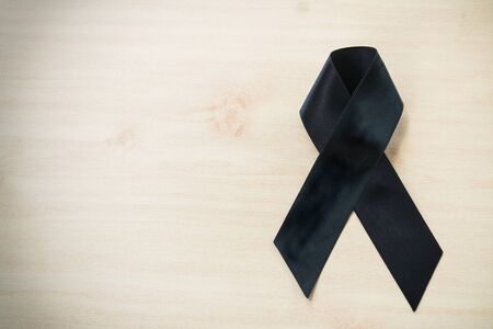 Black mourning ribbon of condolence with wooden backgroundの写真素材
