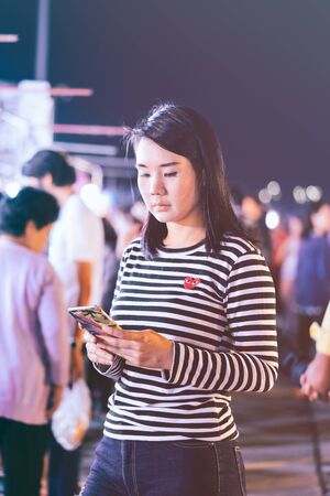 Asian woman using smart phone at street market in Thailand