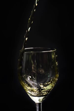 Pour beverage into the glass on black backgroundの写真素材