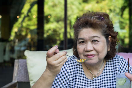 senior asia woman eating foodの写真素材