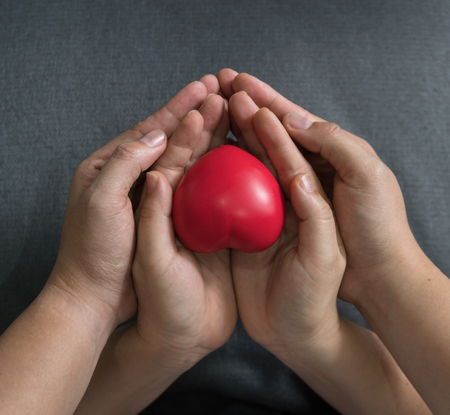 Closeup of hands holding red heart shapeの写真素材
