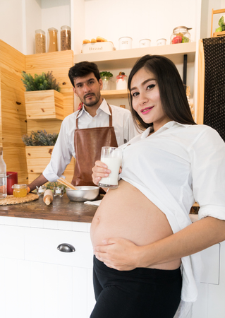 pregnant wife and husband cooking in the kitchenの写真素材