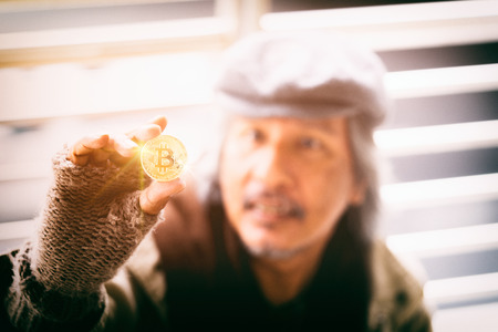 Homeless man holding receive donation a golden bitcoin. 