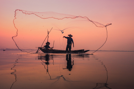 Fishermen using nets to catch fish at the Bangpra lake during sunrise time.の写真素材