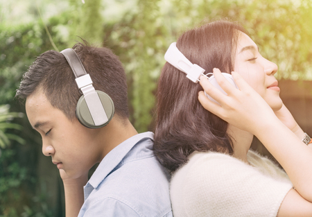 Young couple standing in the park and listening music form headphone