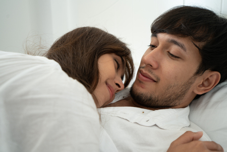 Lovely couple hugging on their bed at homeの写真素材
