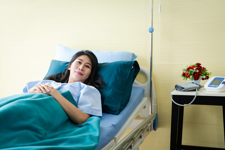 Smiling female patient lying in hospital bedの写真素材