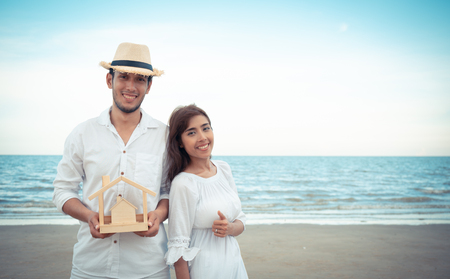 Yong family with wooden house model and enjoy on the beachの写真素材
