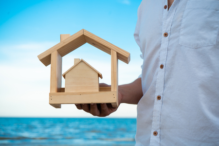 Close up of hand holding wooden houseの写真素材