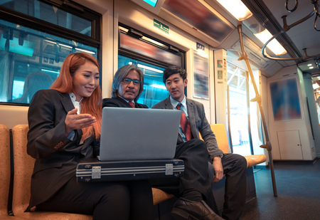 Business man and woman are discussing about their project on the trainの写真素材