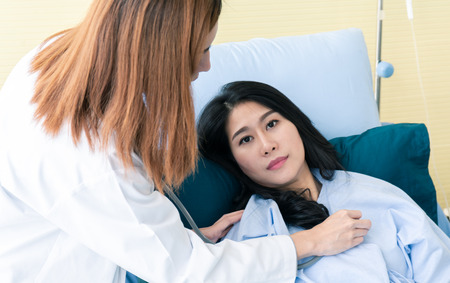 Team of doctor examining a female patient on bed in hospitalの写真素材