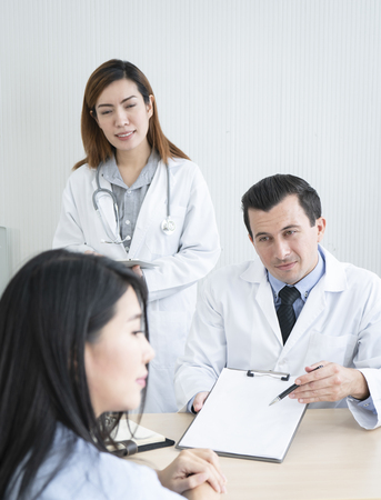 Team of doctor explain resault to female patient in hospitalの写真素材