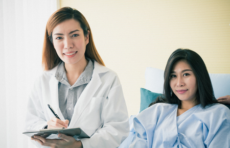 Smiling doctor examining  female patient on bedの写真素材
