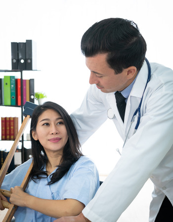 Smiling doctor and Medical Assistant takecare to disabled patient on wheelchairの写真素材