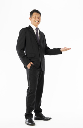 Business man in black suit standing and open hand to copyspace on white backgroundの写真素材