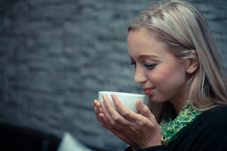 Young woman drinking hot coffee at the coffee shop
