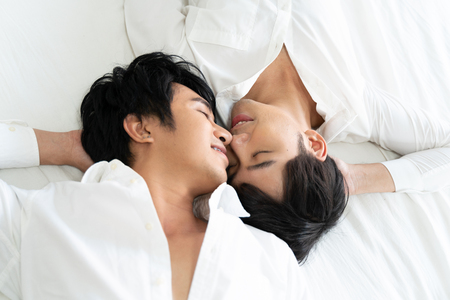 Gay couple spending time in bed and takecare hugging and kissing together.の写真素材