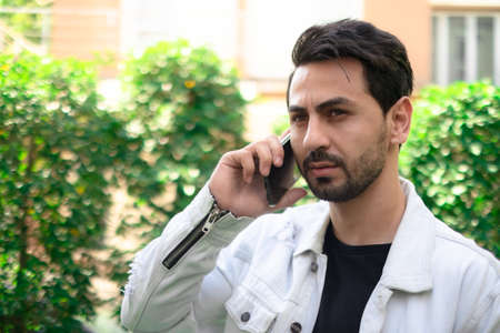 A young man in casual standing and talking mobile.の写真素材