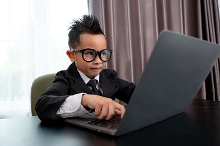 Little boy in Busines suit working with notebook in office.の写真素材
