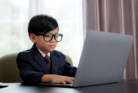 Little boy in Busines suit working with notebook in office.の写真素材