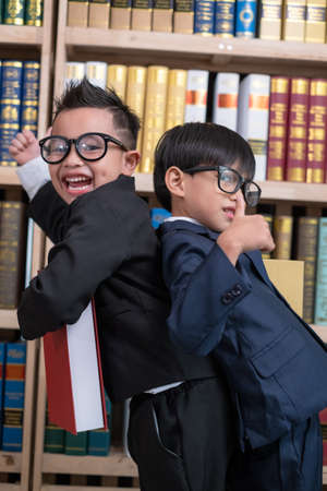 Little boys in suit looking and choose book in shelf.の写真素材