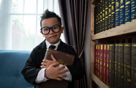 Little boys in suit looking and choose book in shelf.の写真素材