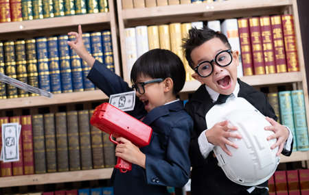 Little boys in suits use the cash cannon with money and Another boy holding engineer hat.の写真素材